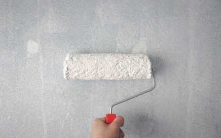 person holding paint roller on wall